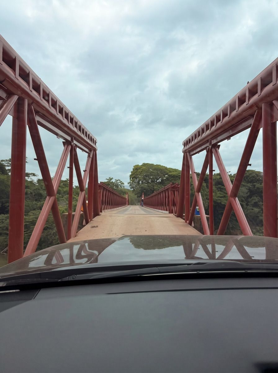 Vista desde el tablero de un vehículo entrando a un puente de acero rojo